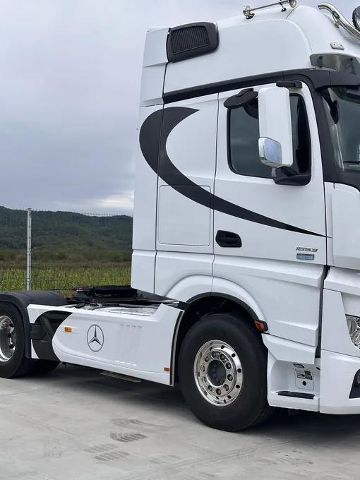 Grafică decorativă neagră pe cabina albă a unui camion Mercedes, partea dreaptă
